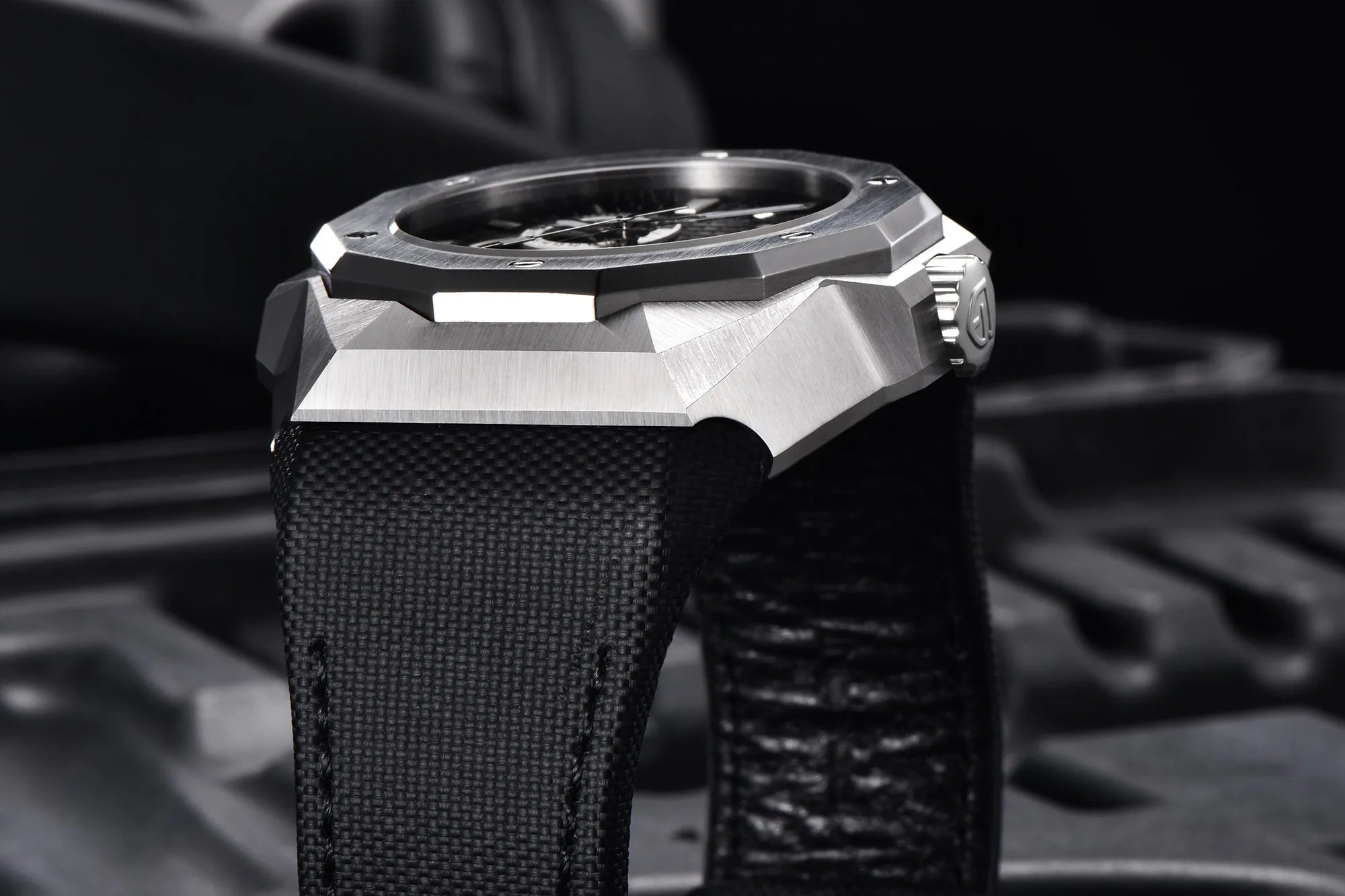 Close-up of a silver watch with a black strap on a blurred background