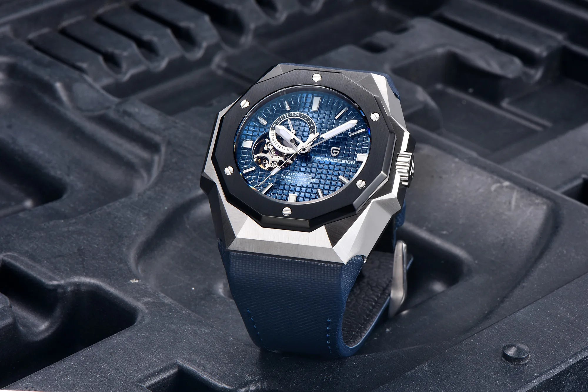 Luxury watch with blue face and strap on a textured black surface