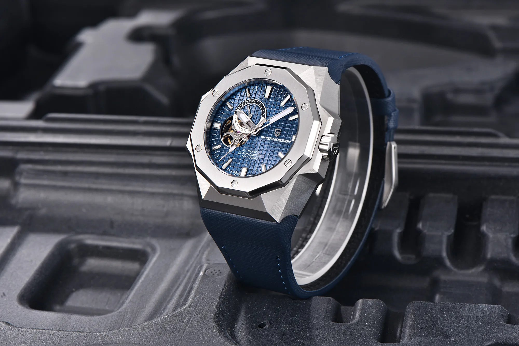 Luxury watch with blue strap and detailed face on a textured black background